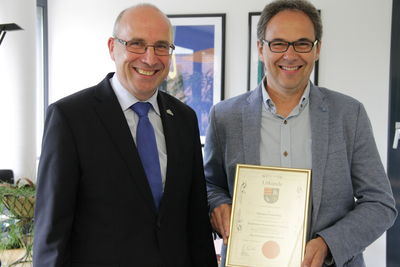 Bild vergrößern: Thomas Enneking (rechts) freut sich über die Auszeichnung, die er von Bürgermeister Gerd Muhle für sein ehrenamtliches Engagement bekommt