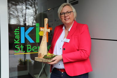 Bild vergrößern: Karin Bolke hält ein Kreuz aus Wurzelholz, das von den Benediktinerinnen aus Dinklage stammt, in der Hand